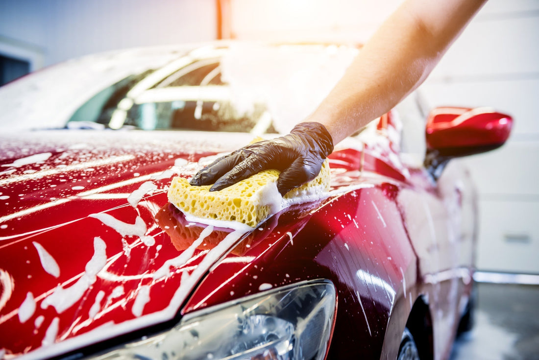 red car with soap suds covering it while its being washed