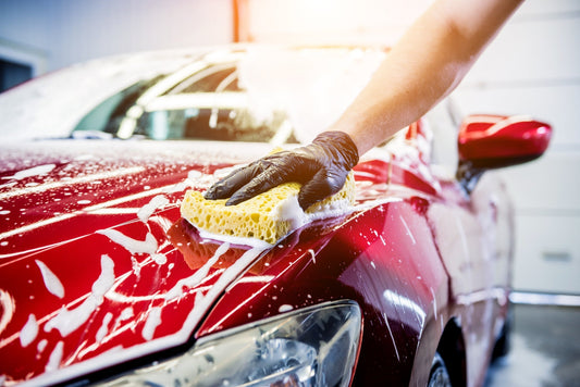 red car with soap suds covering it while its being washed