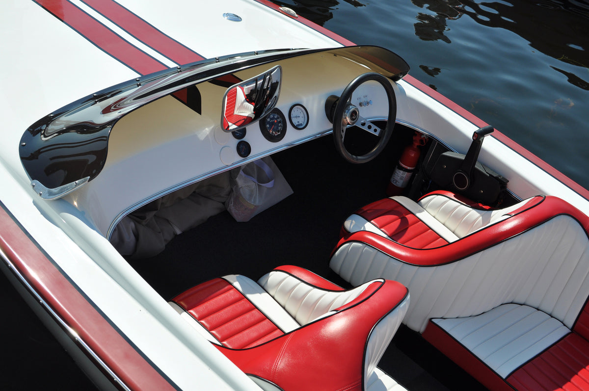 Close-up of a boat's interior with red and white seats and dashboard.