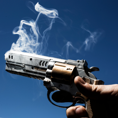 Holding a gun that is smoking from the barrel