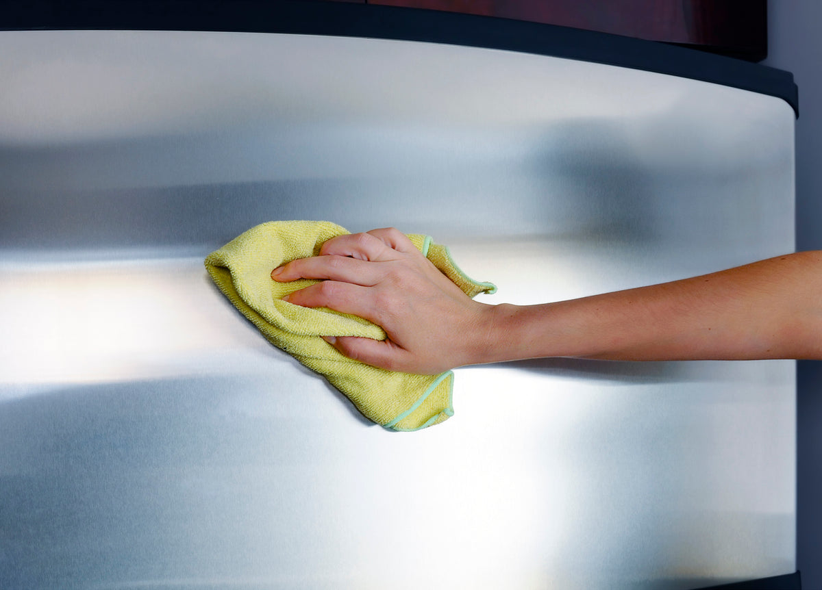 Person cleaning a metallic surface with a yellow cloth