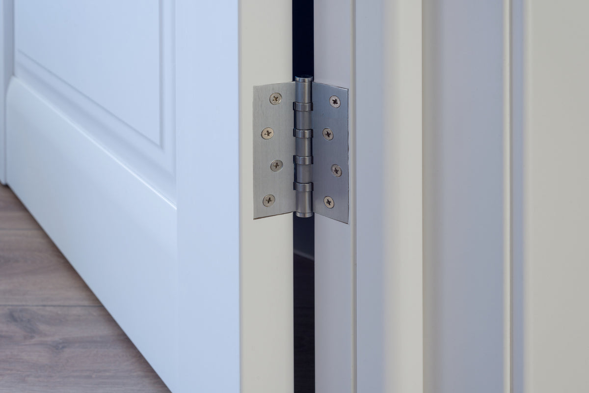 Close-up of a door hinge on a white door