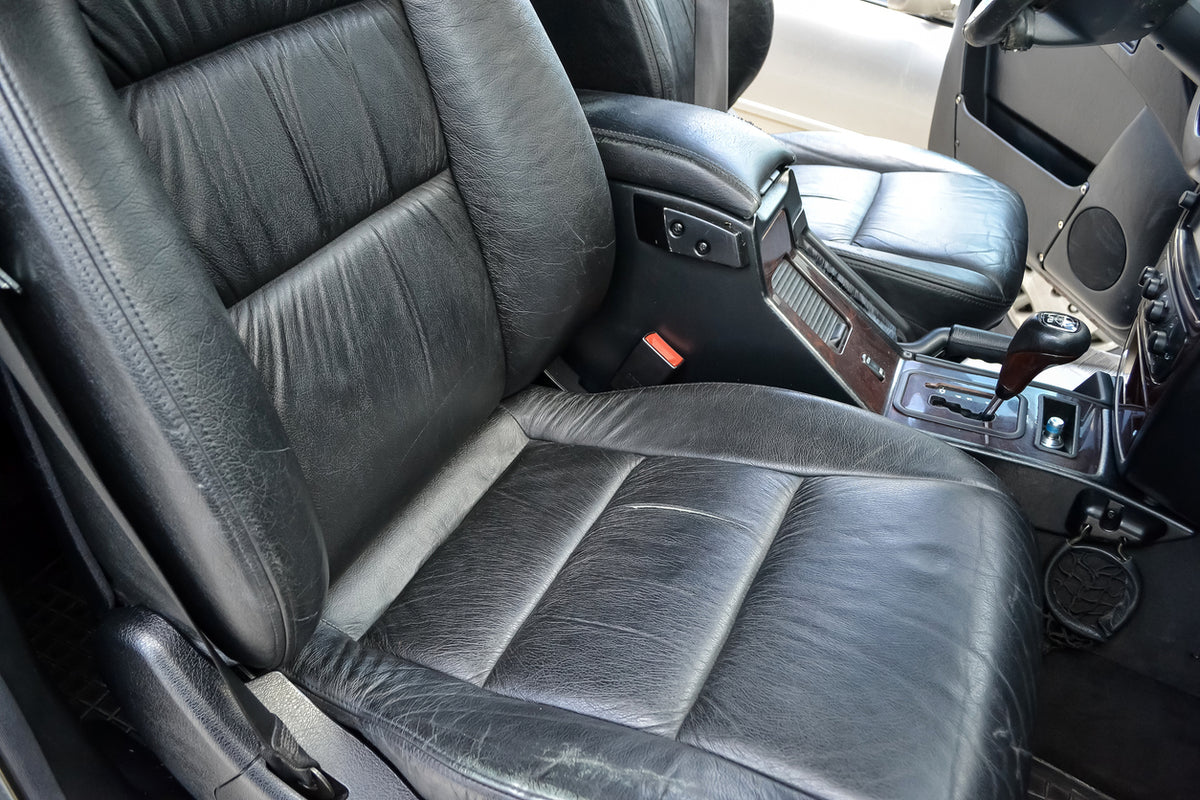 Close-up of a car's black leather seat with interior details.