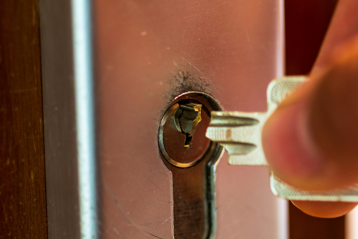 Close-up of a key being inserted into a lock on a wooden door.